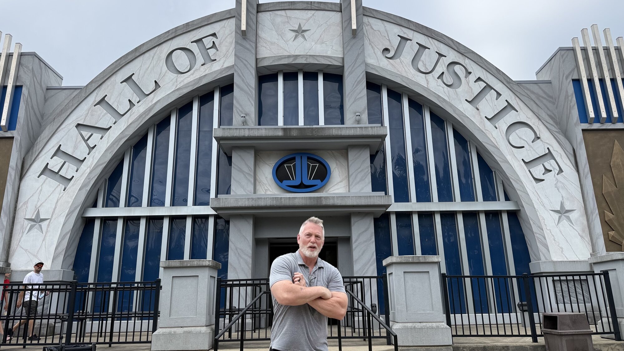 Doug Mahnke standing with arms crossed in front of the Hall of Justice