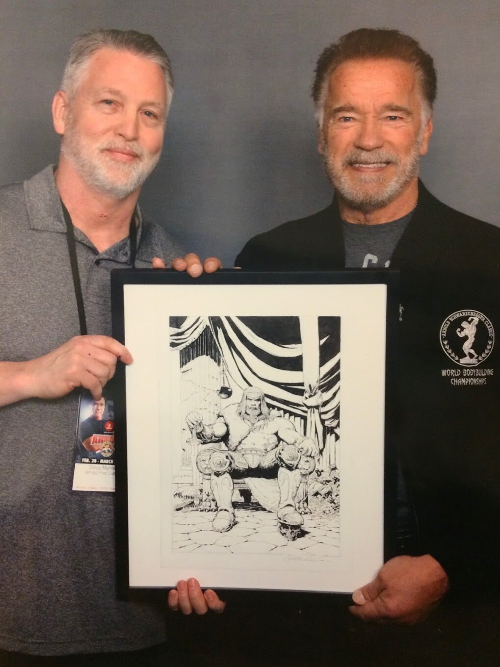 Doug Mahnke with Arnold Schwarzenegger, holding a framed barbarian drawing